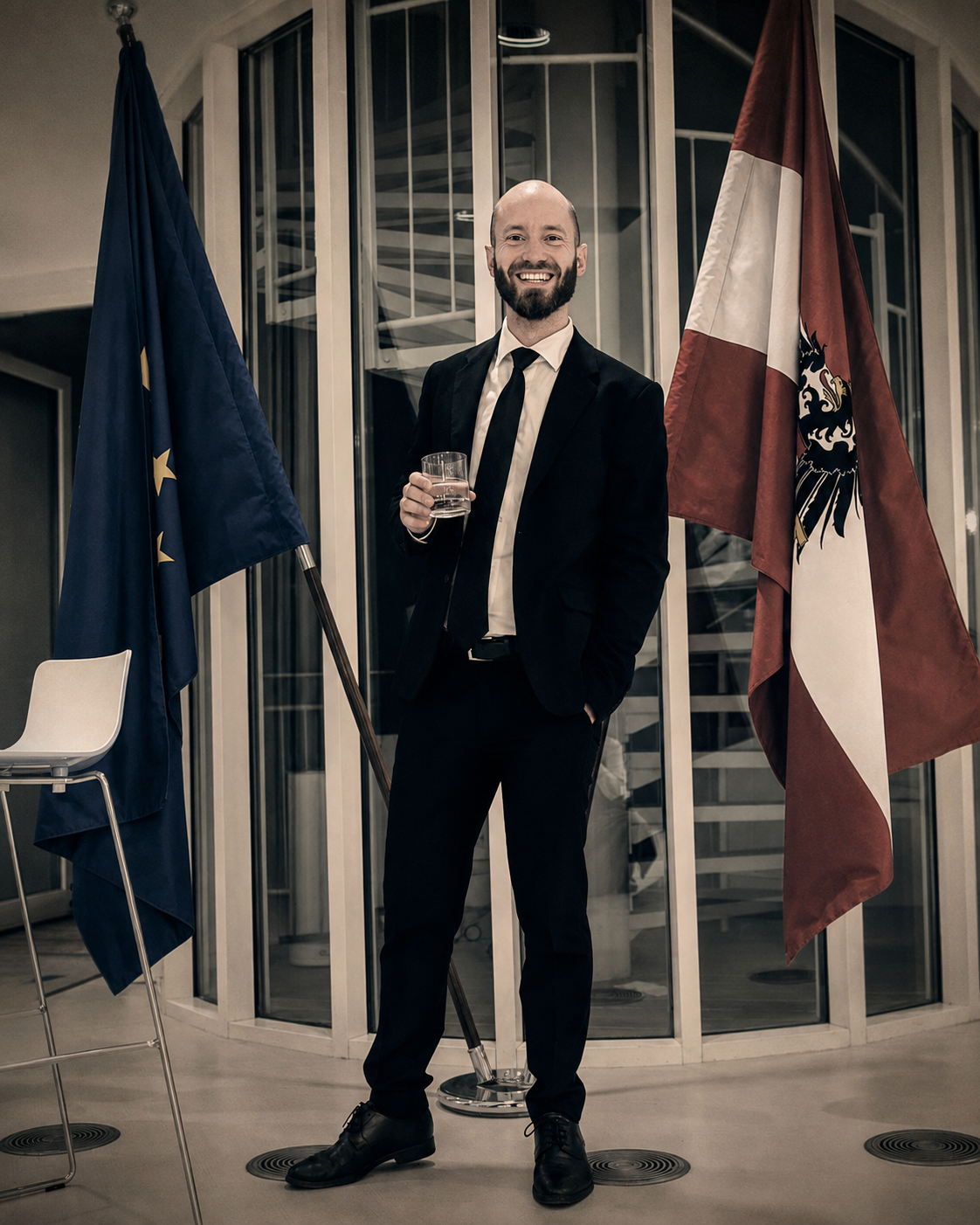 Dorian Rammer im Anzug zwischen der österreichischen und der europäischen Flagge